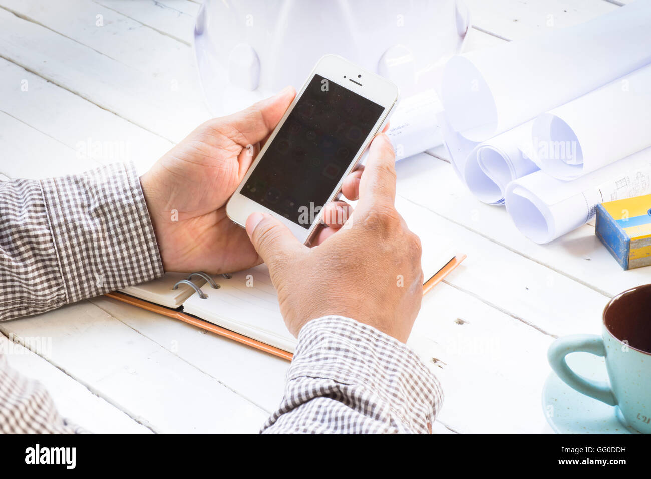 Uomo con lo smartphone nel luogo di lavoro. Agosto 1.Smartphone in mano gli architetti con apparecchiature di sfondo per lavoro.Close up. Foto Stock