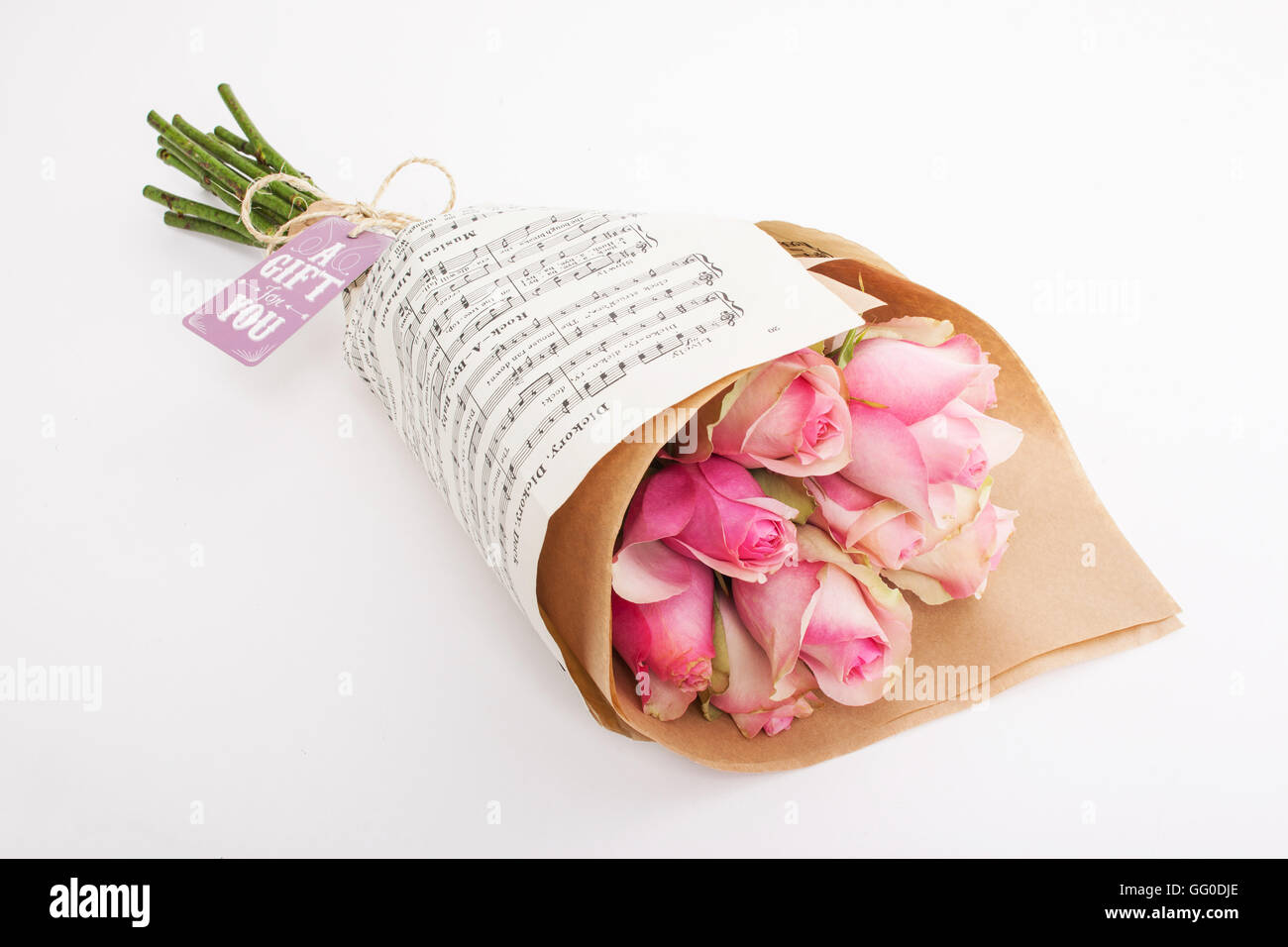 Dono bouquet di rose rosa avvolto in carta da musica con una carta regalo e tirante Foto Stock