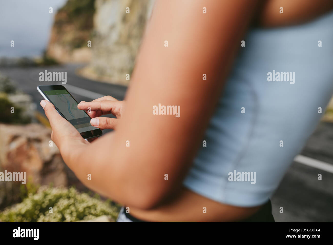 Immagine ritagliata del femminile tenendo il telefono cellulare. Montare donna utilizzando il cellulare all'aperto dopo una sessione di formazione. Foto Stock Immagine ritagliata del femminile tenendo il telefono cellulare. Montare donna utilizzando il cellulare all'aperto dopo una sessione di formazione. Foto Stock