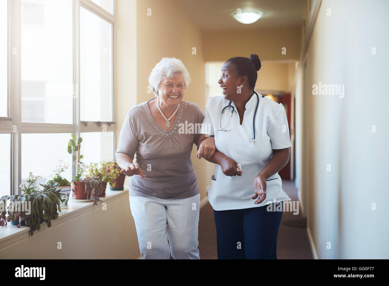 Ritratto di felice lavoratore del settore sanitario e senior donna camminare insieme. Paziente senior di divertirsi con la sua casa operatore sanitario. Foto Stock