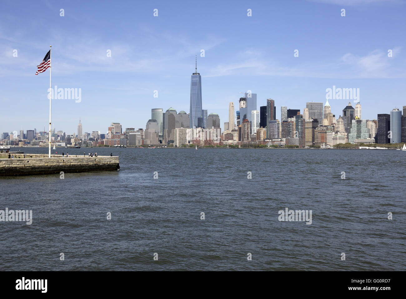 Skyline di Manhattan il quartiere finanziario della città di New York con una bandiera degli Stati Uniti su Liberty Island in primo piano.New York,USA Foto Stock