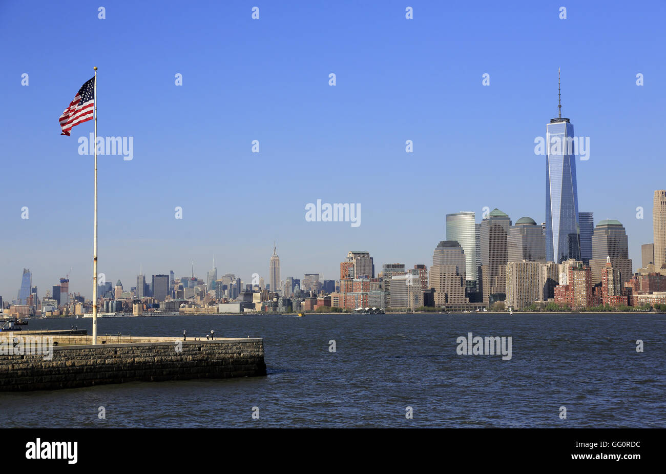 Skyline di Manhattan il quartiere finanziario della città di New York con una bandiera degli Stati Uniti su Liberty Island in primo piano.New York,USA Foto Stock