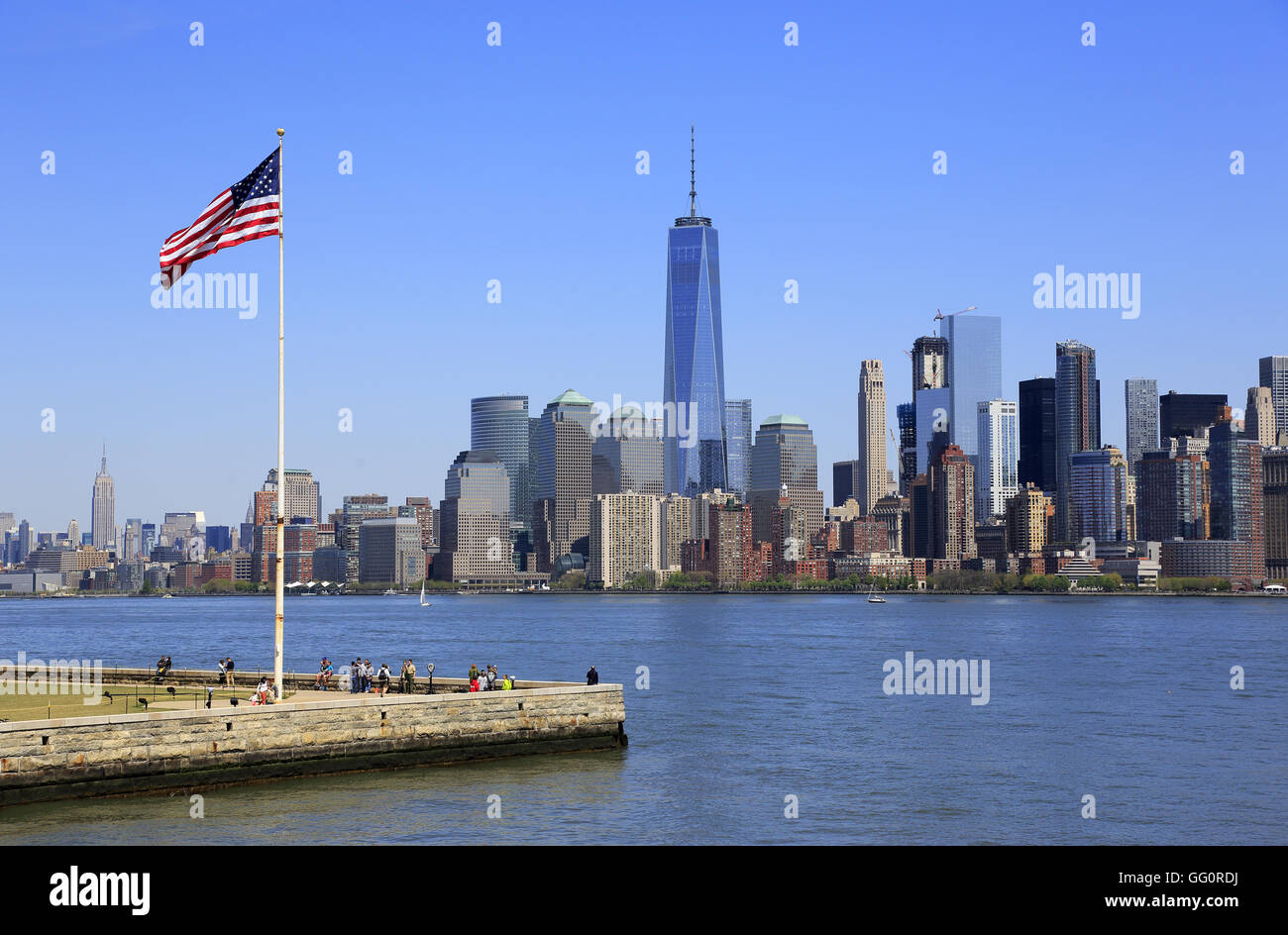 Skyline di Manhattan il quartiere finanziario della città di New York con una bandiera degli Stati Uniti su Liberty Island in primo piano.New York,USA Foto Stock