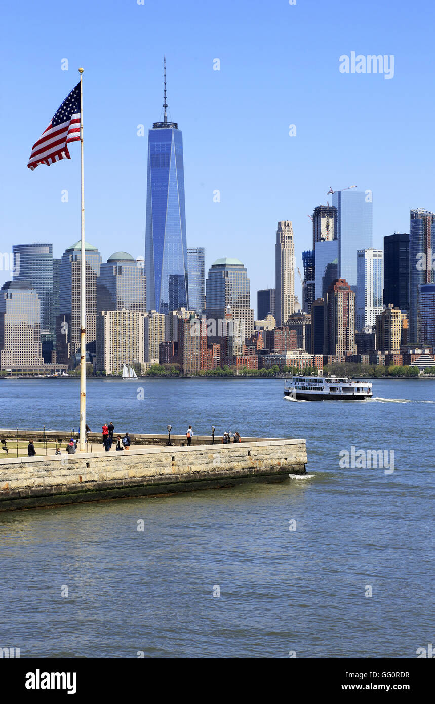 Skyline di Manhattan il quartiere finanziario della città di New York con una bandiera degli Stati Uniti su Liberty Island in primo piano.New York,USA Foto Stock