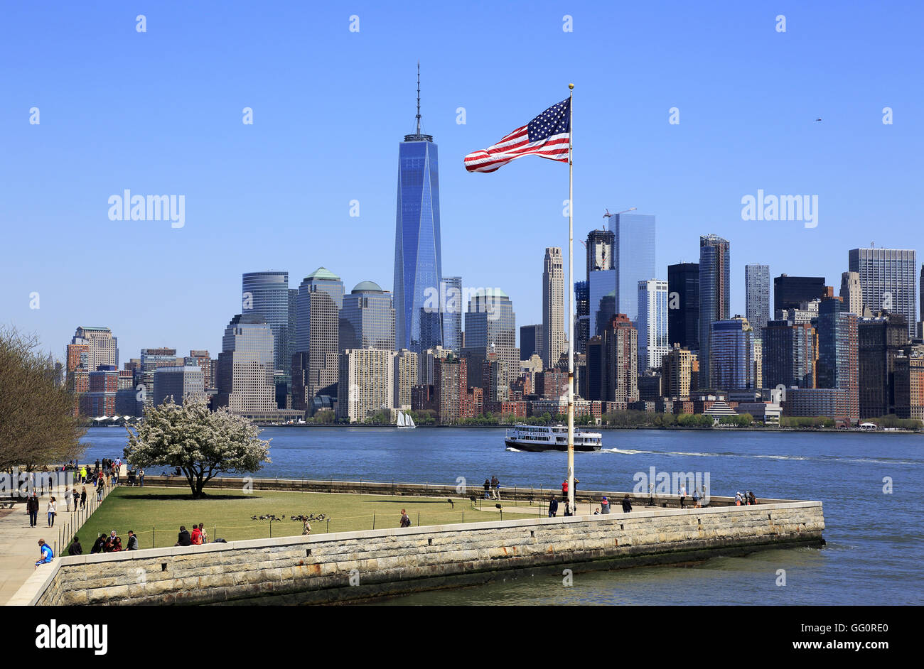 Skyline di Manhattan il quartiere finanziario della città di New York con una bandiera degli Stati Uniti su Liberty Island in primo piano.New York,USA Foto Stock