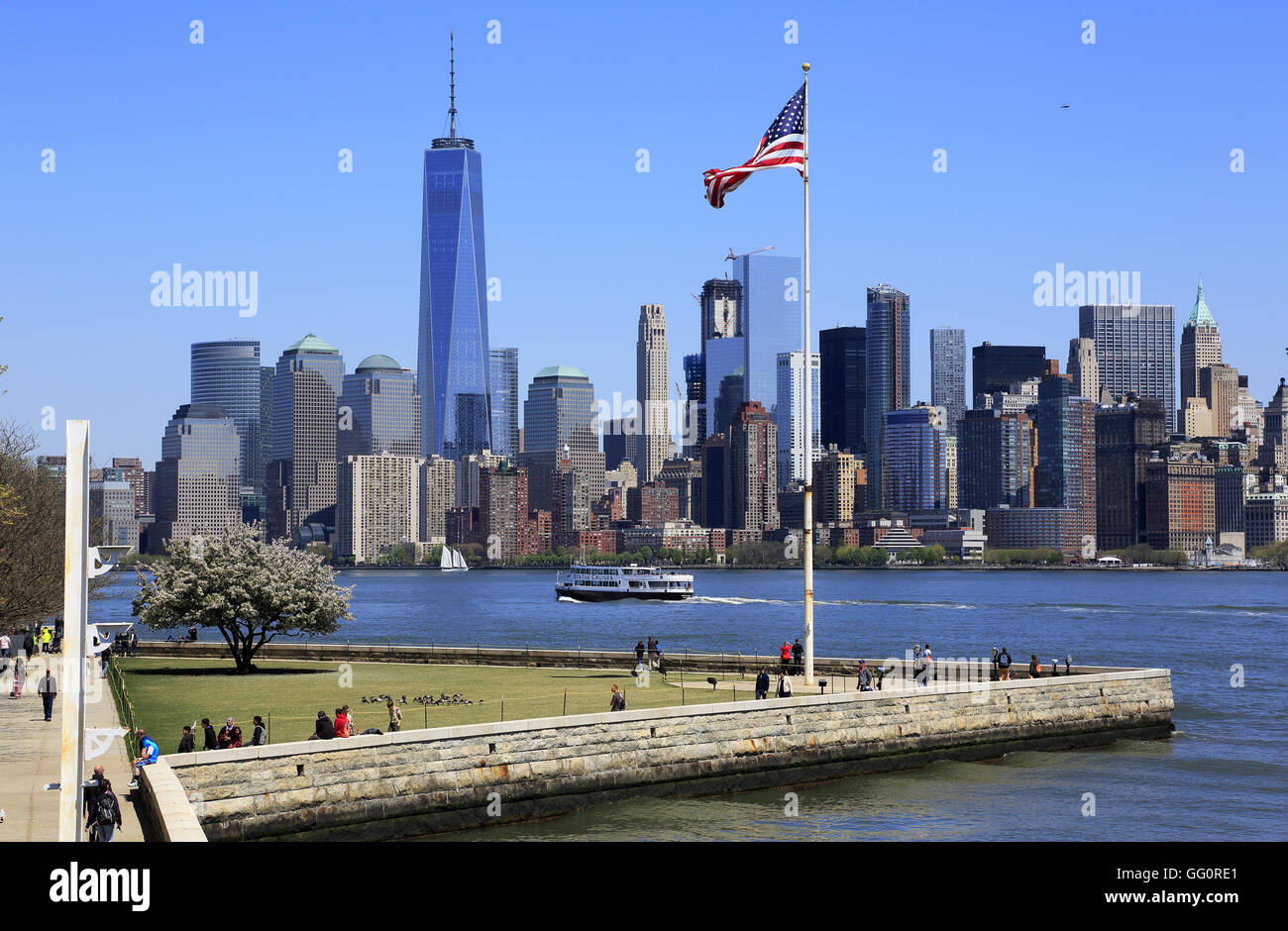 Skyline di Manhattan il quartiere finanziario della città di New York con una bandiera degli Stati Uniti su Liberty Island in primo piano.New York,USA Foto Stock