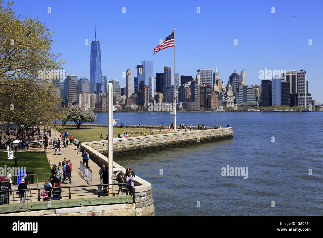 Skyline di Manhattan il quartiere finanziario della città di New York con una bandiera degli Stati Uniti su Liberty Island in primo piano.New York,USA Foto Stock