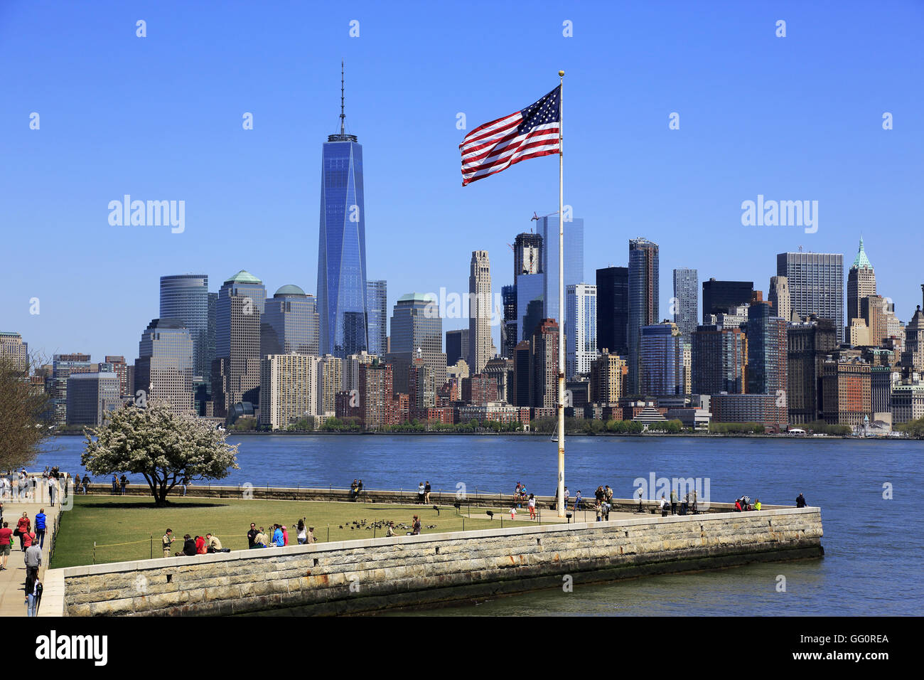 Skyline di Manhattan il quartiere finanziario della città di New York con una bandiera degli Stati Uniti su Liberty Island in primo piano.New York,USA Foto Stock