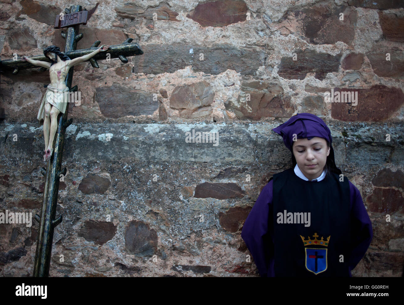 Un giovane adolescente sorge da un Crocifisso durante una PASQUA SETTIMANA SANTA PROCESSIONE in Astorga, Castilla y Leon, Spagna. Foto Stock