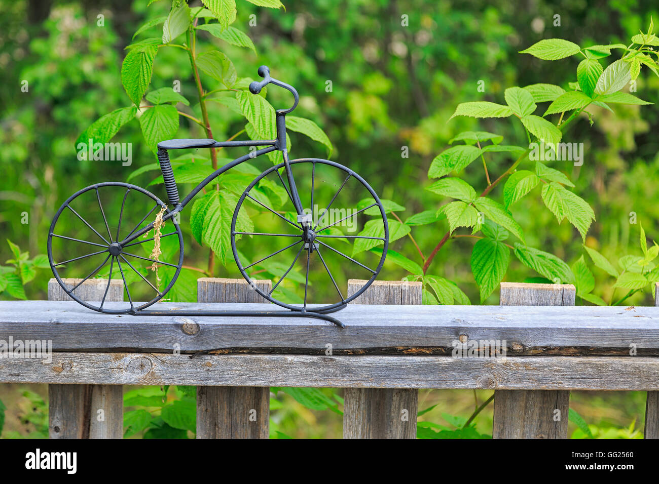 Un po' di ornamento di bicicletta realizzata in ferro battuto sulla parte superiore di un giardino in legno recinzione. Foto Stock