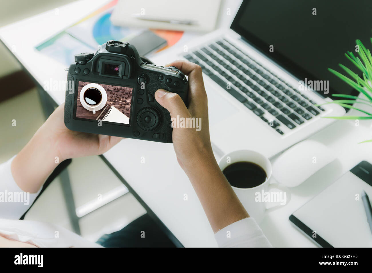 Fotografo tenere la fotocamera controllo foto sulla sua scrivania spazio di lavoro Foto Stock