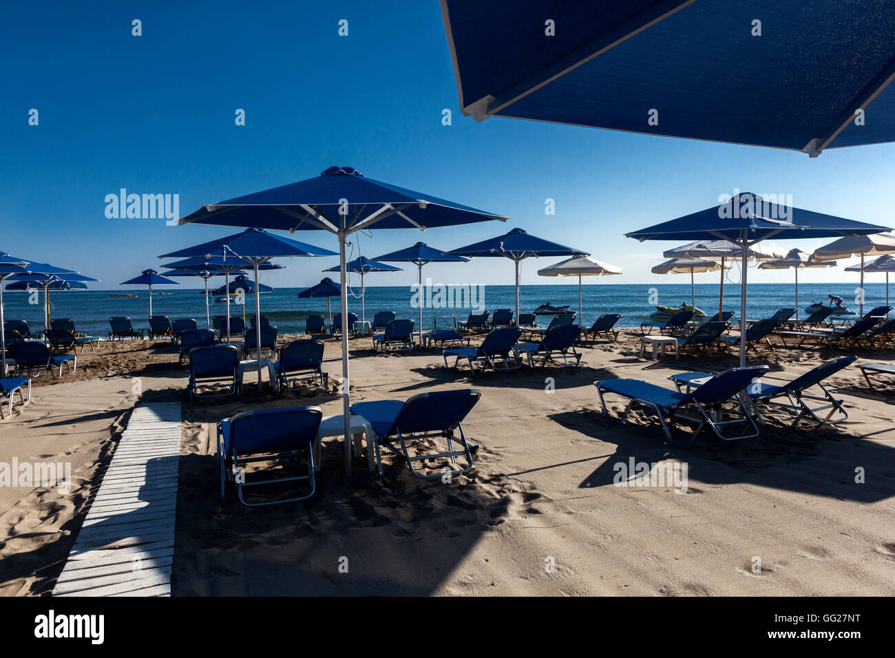 Ombrelloni e lettini in blu ingresso alla spiaggia di Rethymno, Creta spiaggia Grecia, spiaggia pronta per l'arrivo dei vacanzieri Foto Stock