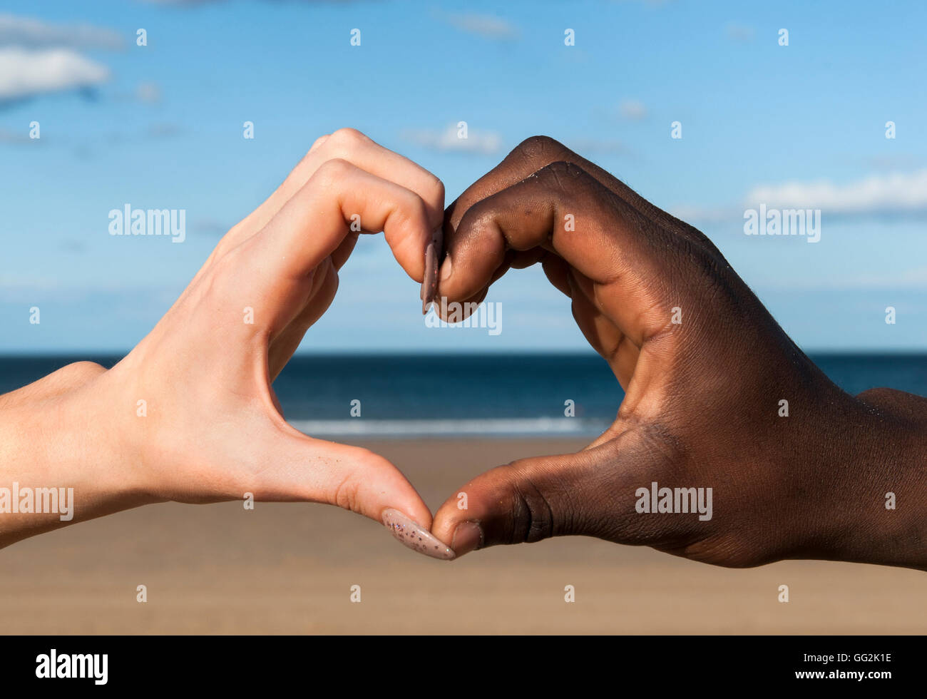 Cuore mani Mani multiculturale maschio e femmina in forma di cuore a beach amare la pace stare insieme Foto Stock