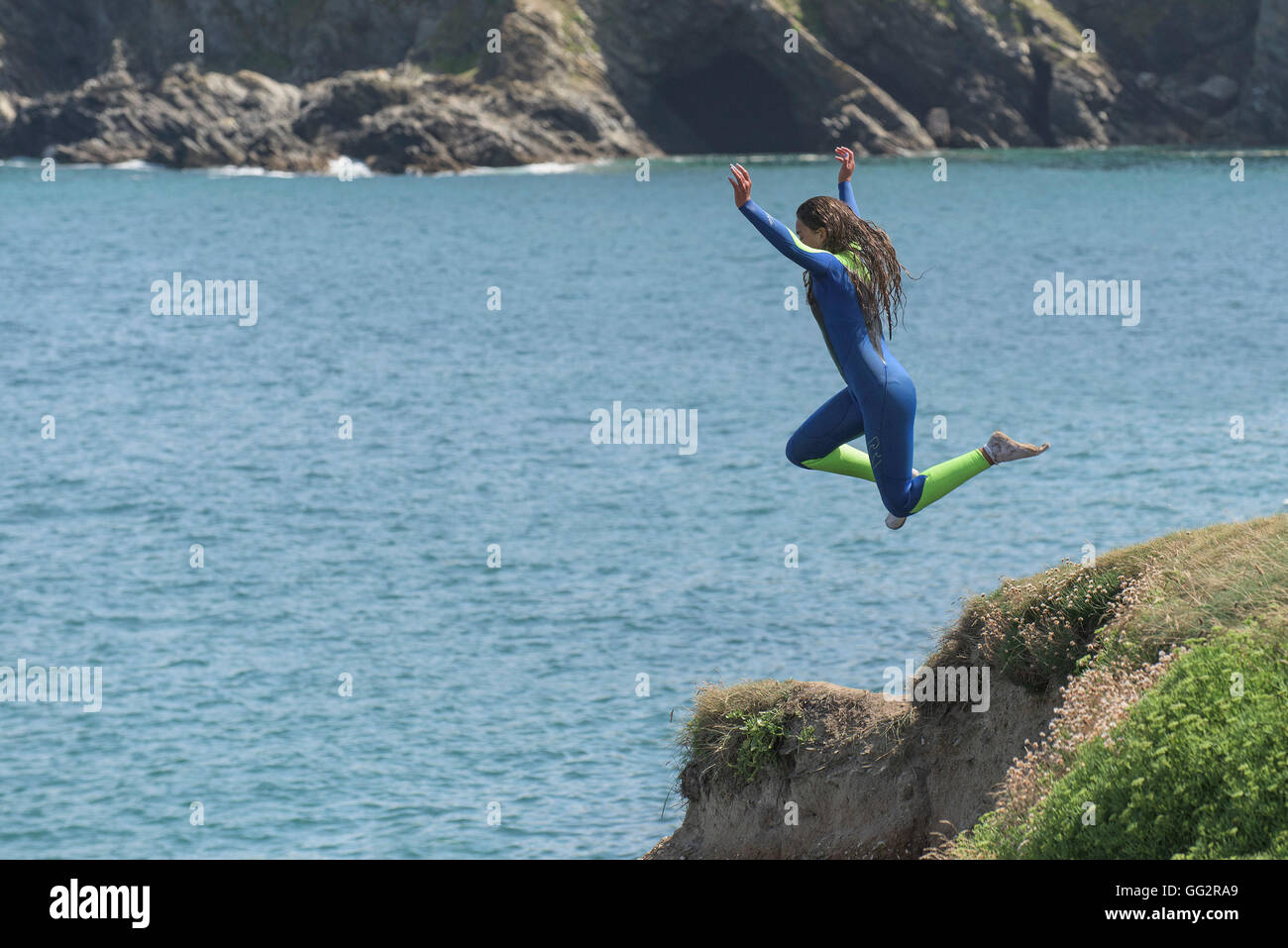 Un giovane adolescente tombstoning off scogliere in Newquay, Cornwall. Foto Stock