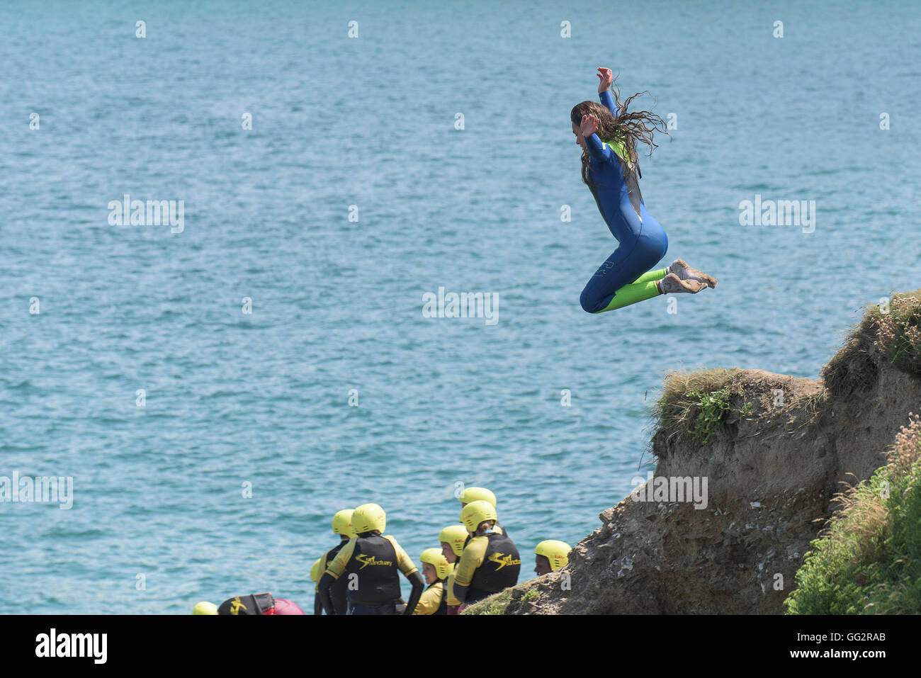Un giovane adolescente tombstoning off scogliere in Newquay, Cornwall. Foto Stock