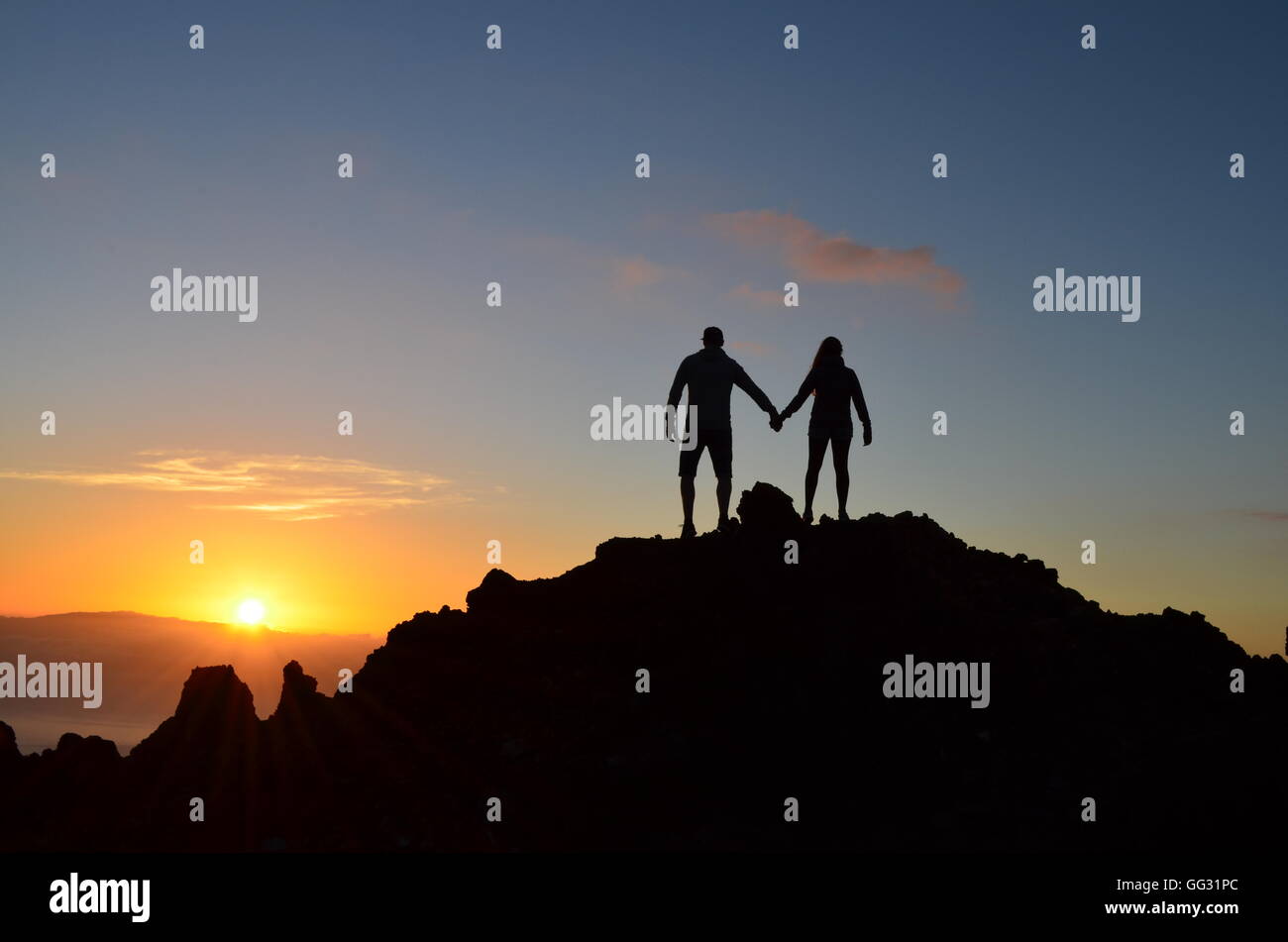 Un paio di piedi al tramonto su una montagna e si possono vedere le sagome tenendo le mani Foto Stock