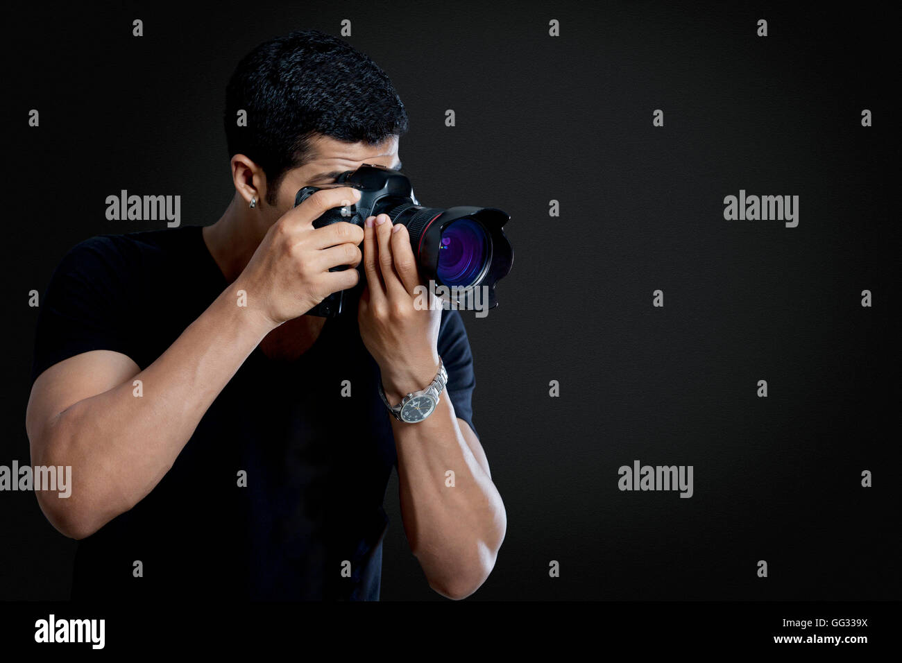 Fotografo maschio tenendo fotografia su sfondo nero Foto Stock