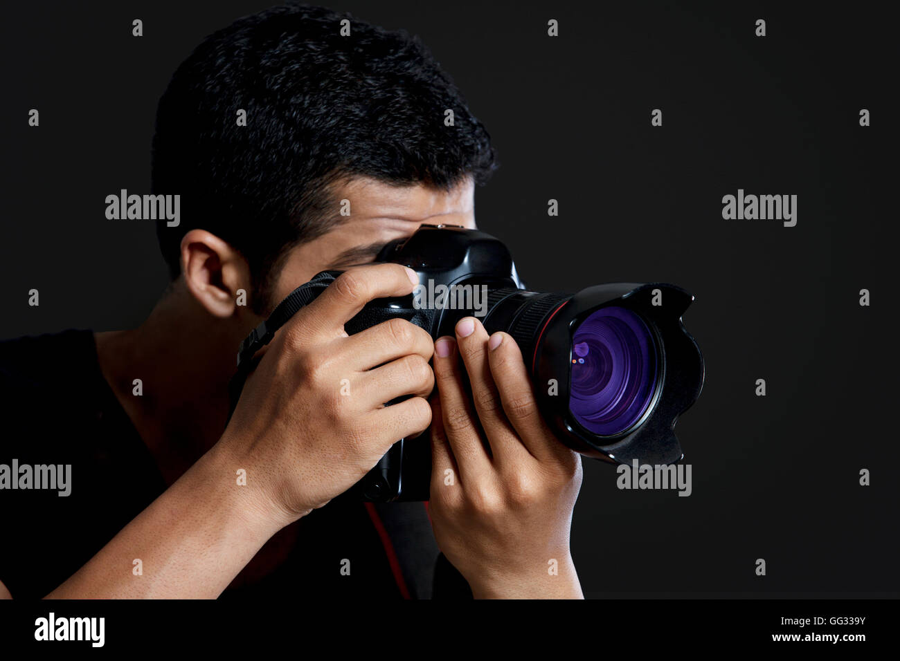 Close-up del fotografo maschio tenendo fotografia su sfondo nero Foto Stock