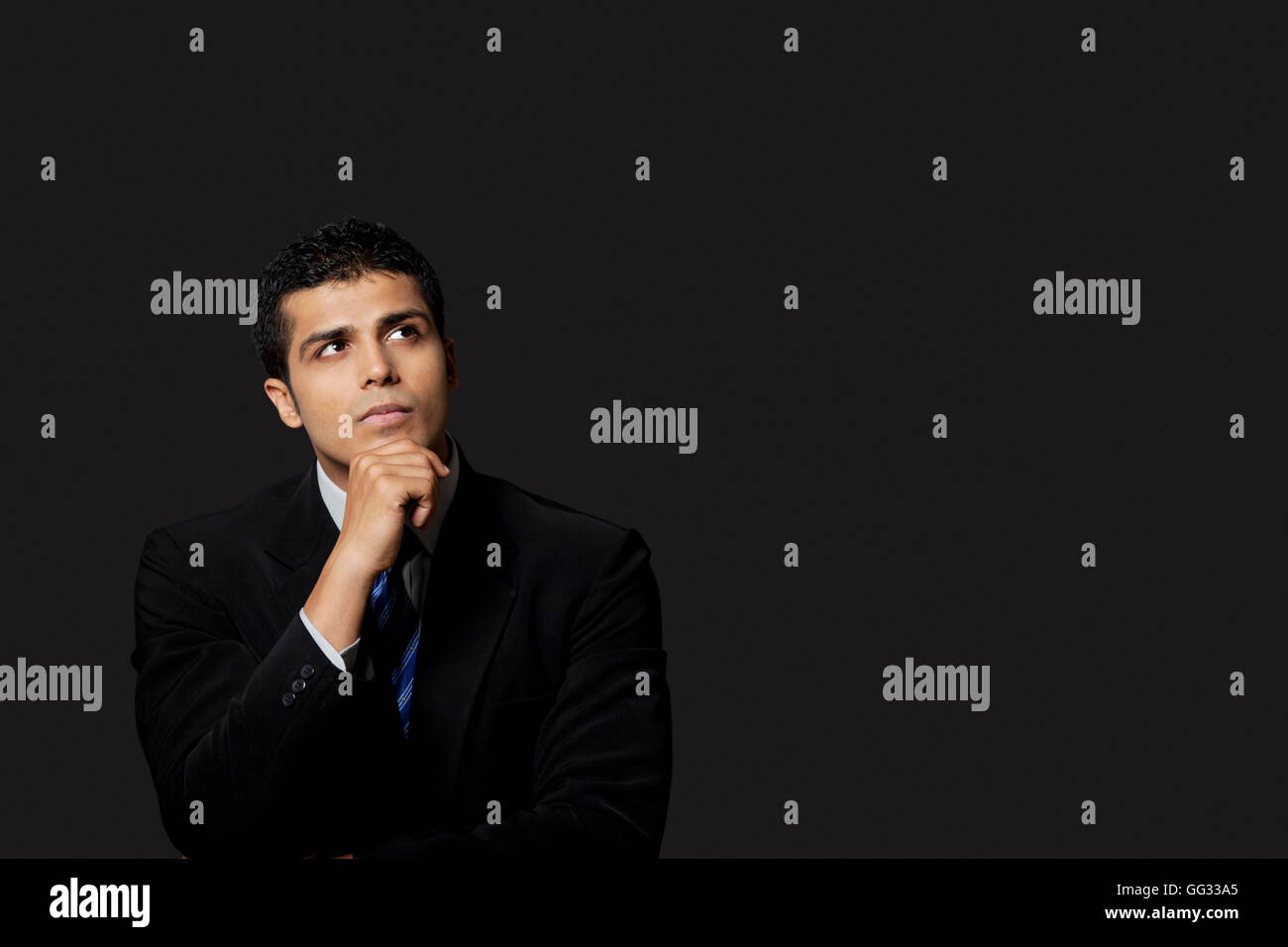 Imprenditore bello guardare lontano su sfondo nero Foto Stock