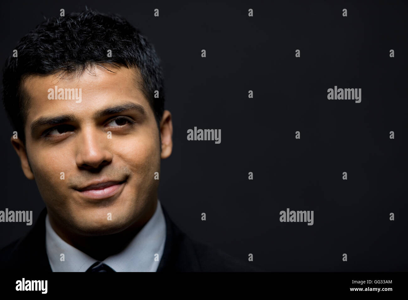 Felice executive maschio contemplando su sfondo nero Foto Stock