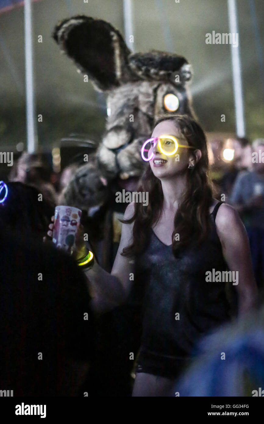 Un festival goer, Lauren Peters, guardando Soulwax a BBC 6Music Tent indossando occhiali luminosi con la luna in background Foto Stock