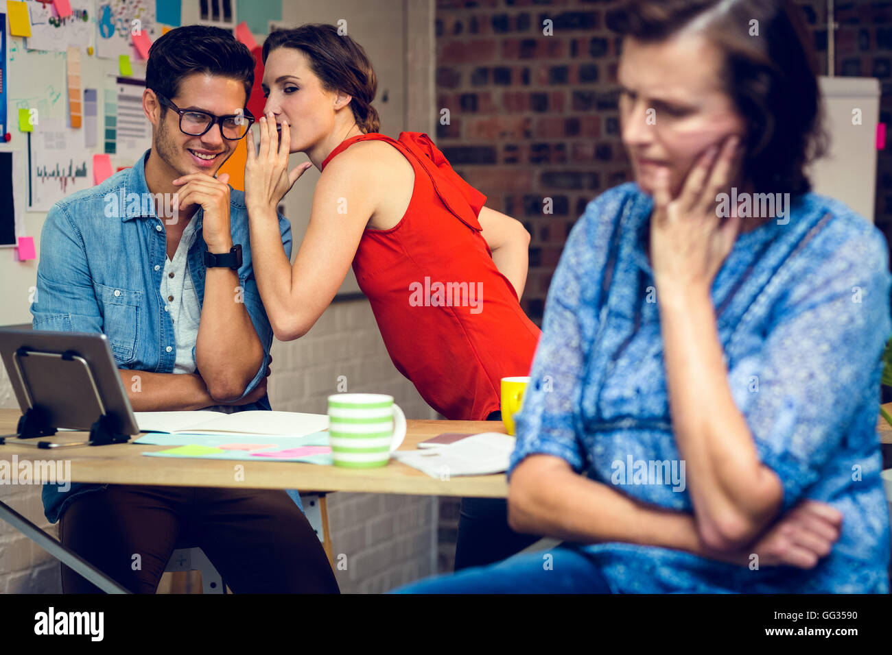 Imprenditrice nel pensiero profondo e colleghi whispering in background Foto Stock