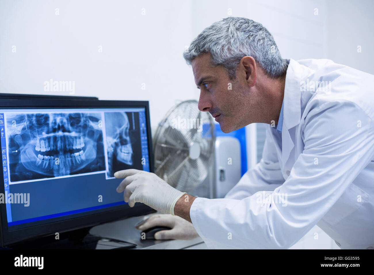 Premuroso dentista esaminando un x-ray sul monitor Foto Stock