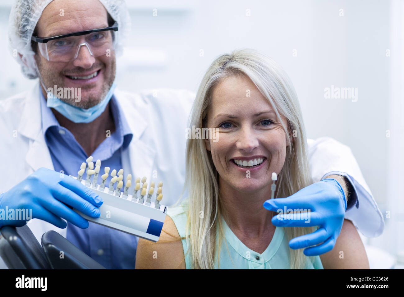 Dentista che mantiene i denti sfumature mentre il paziente donna sorridente Foto Stock
