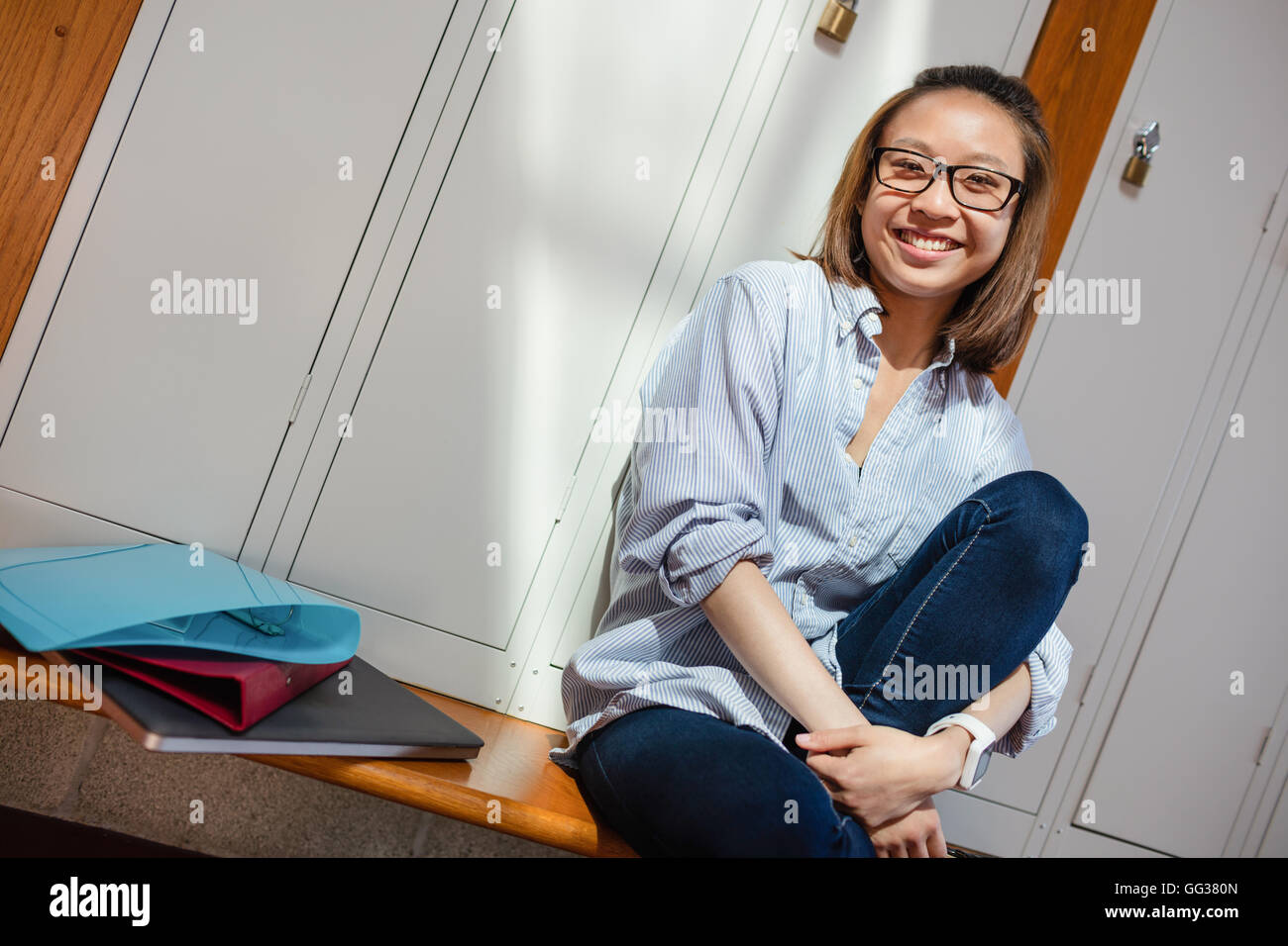Felice giovane donna seduta in spogliatoio Foto Stock