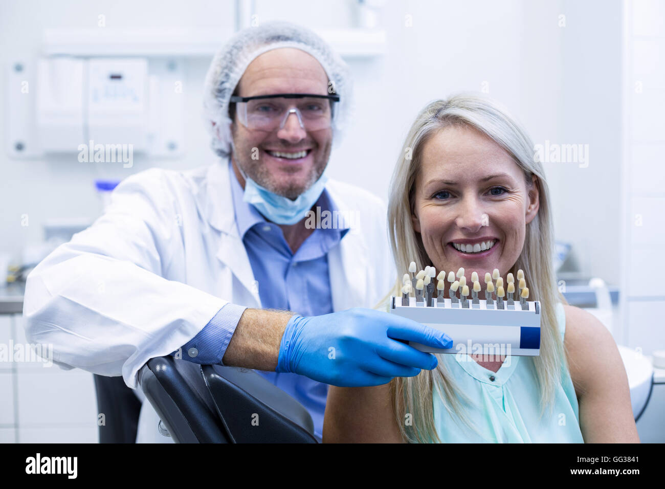 Dentista che mantiene i denti sfumature mentre il paziente donna sorridente Foto Stock