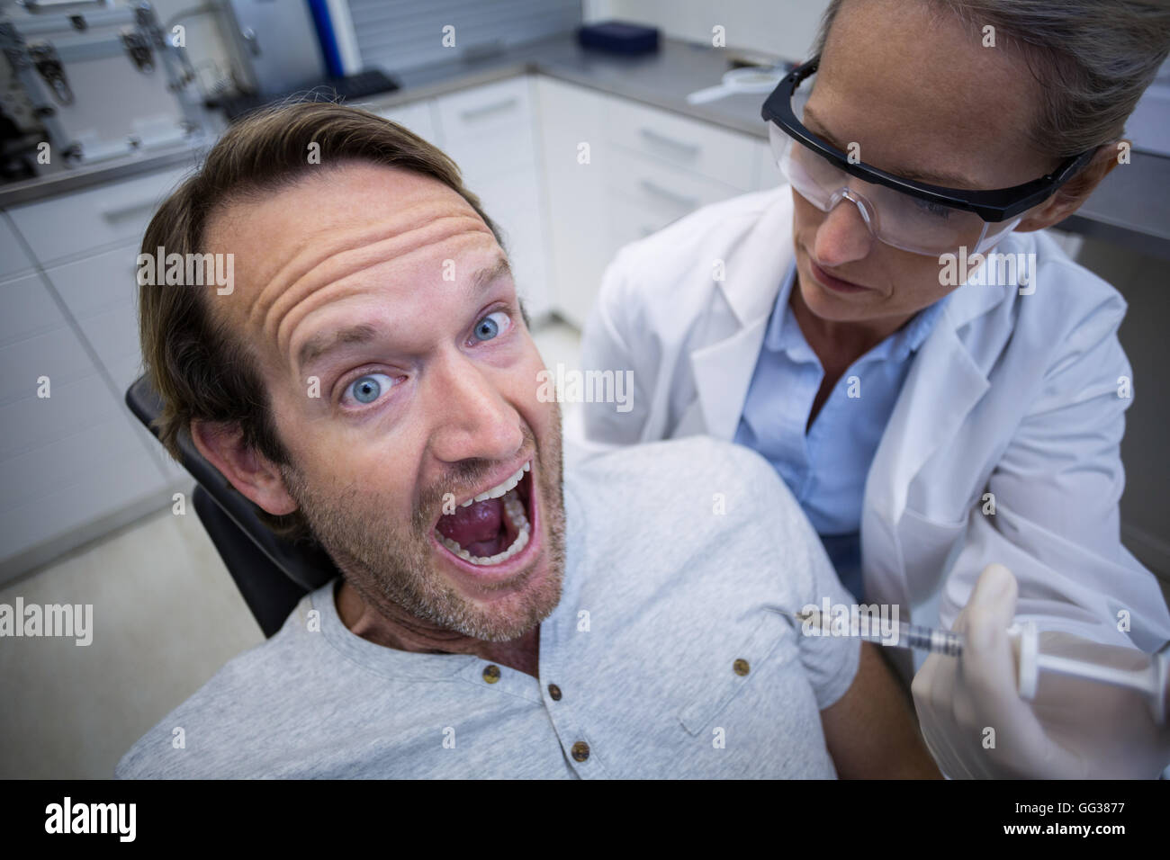 Paziente di sesso maschile spaventata durante un dentista di check-up Foto Stock