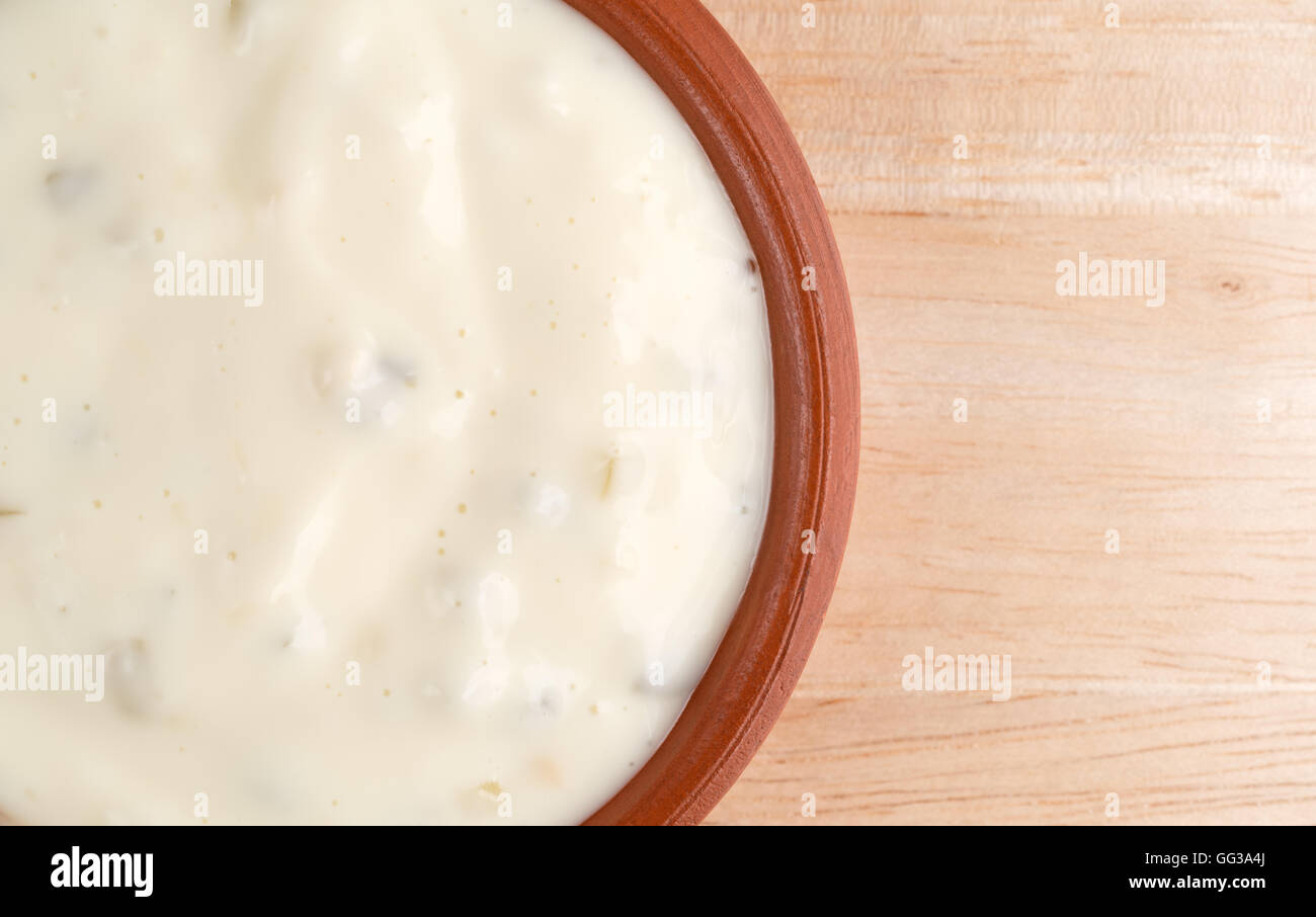 Top vista ravvicinata di una piccola ciotola di argilla di salsa tartara su una tavola di legno. Foto Stock