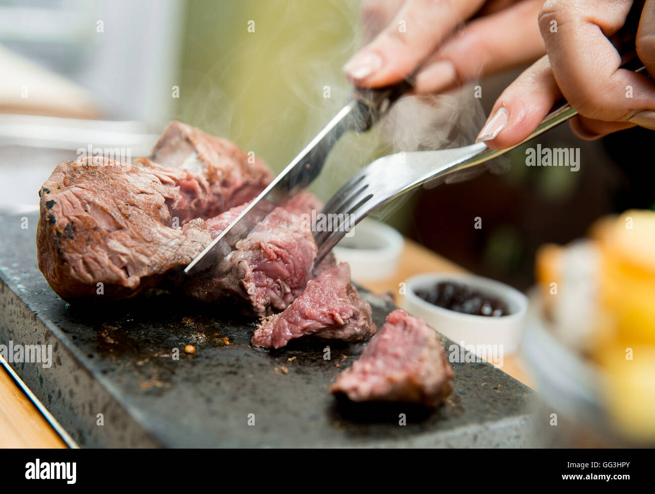 Bistecca di filetto di essere cotti e tagliati su una pietra calda in un ristorante Foto Stock