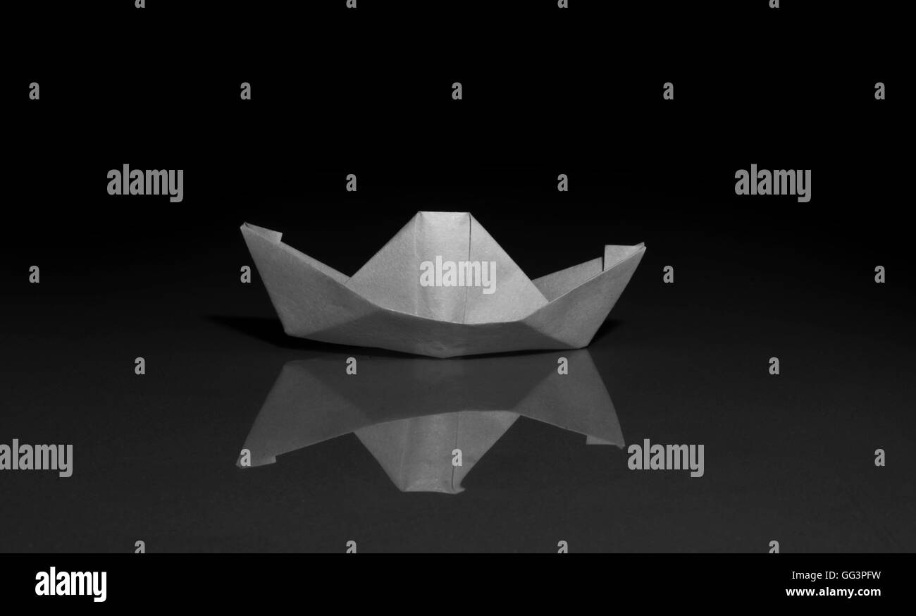 Carta flottante in barca sulle acque blu su sfondo nero Foto Stock
