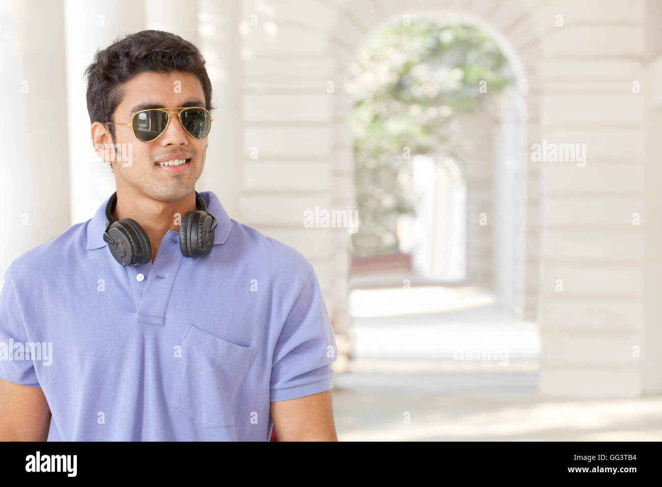 Giovane uomo che indossa gli occhiali da sole che guarda lontano Foto Stock