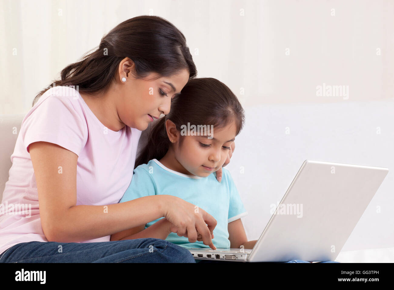 Donna aiutando a sua figlia di utilizzare un computer portatile Foto Stock