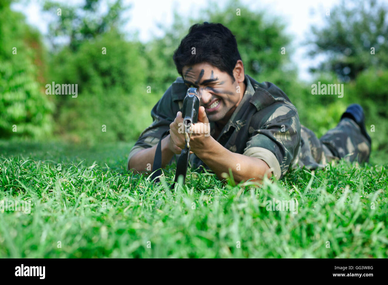 Soldato dell'esercito mirando con un fucile sdraiati sull'erba Foto Stock