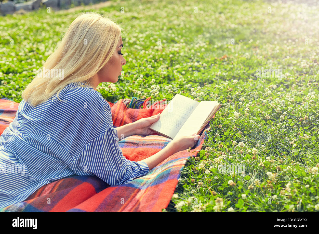 Profilo della ragazza bionda leggere il libro su erba verde Foto Stock