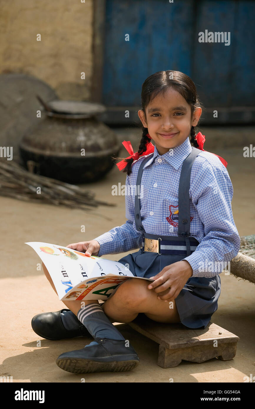 Una scuola rurale ragazza seduta con lei boo Foto Stock