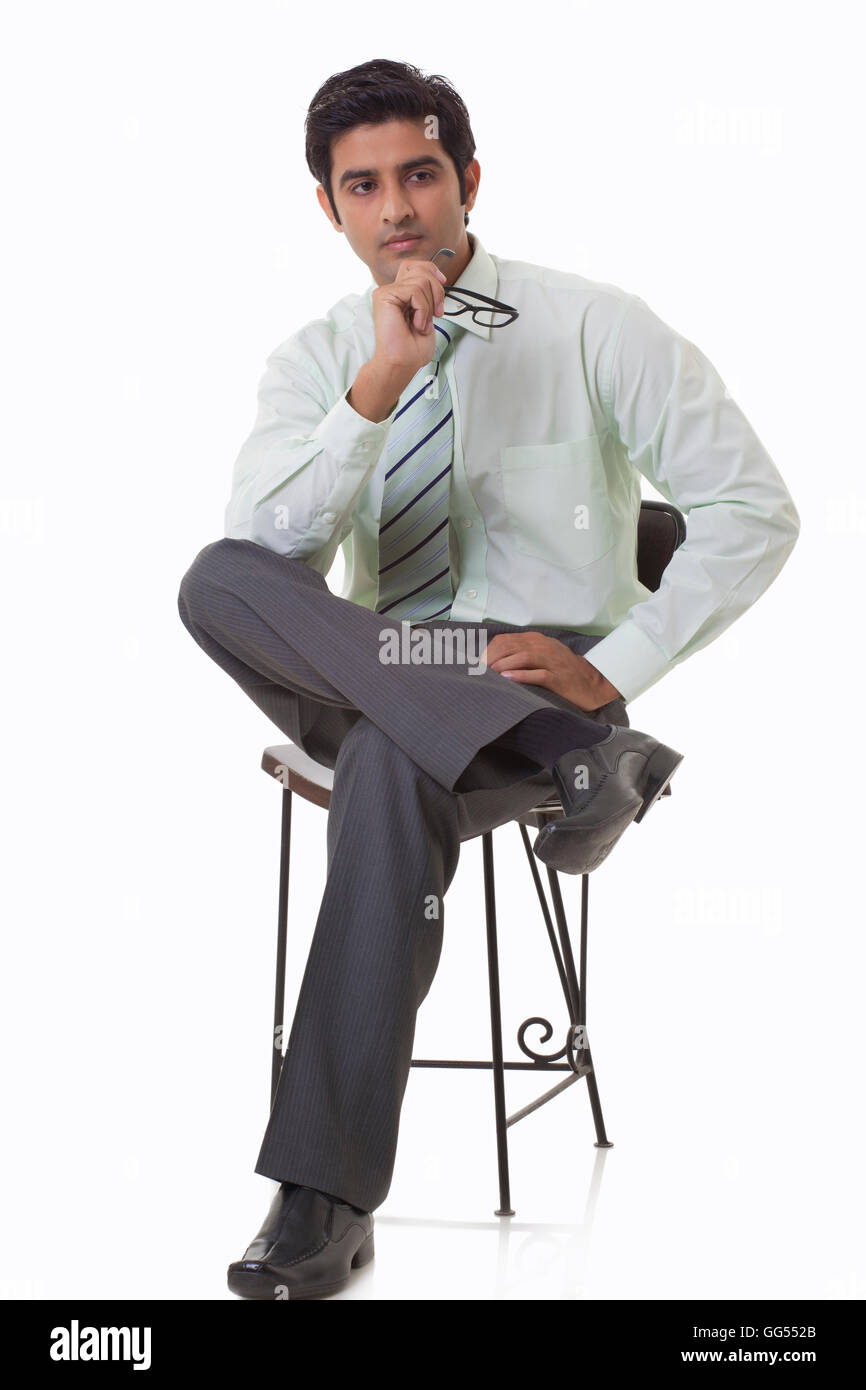 Bel giovane executive seduti su una sedia e guardando lontano Foto Stock