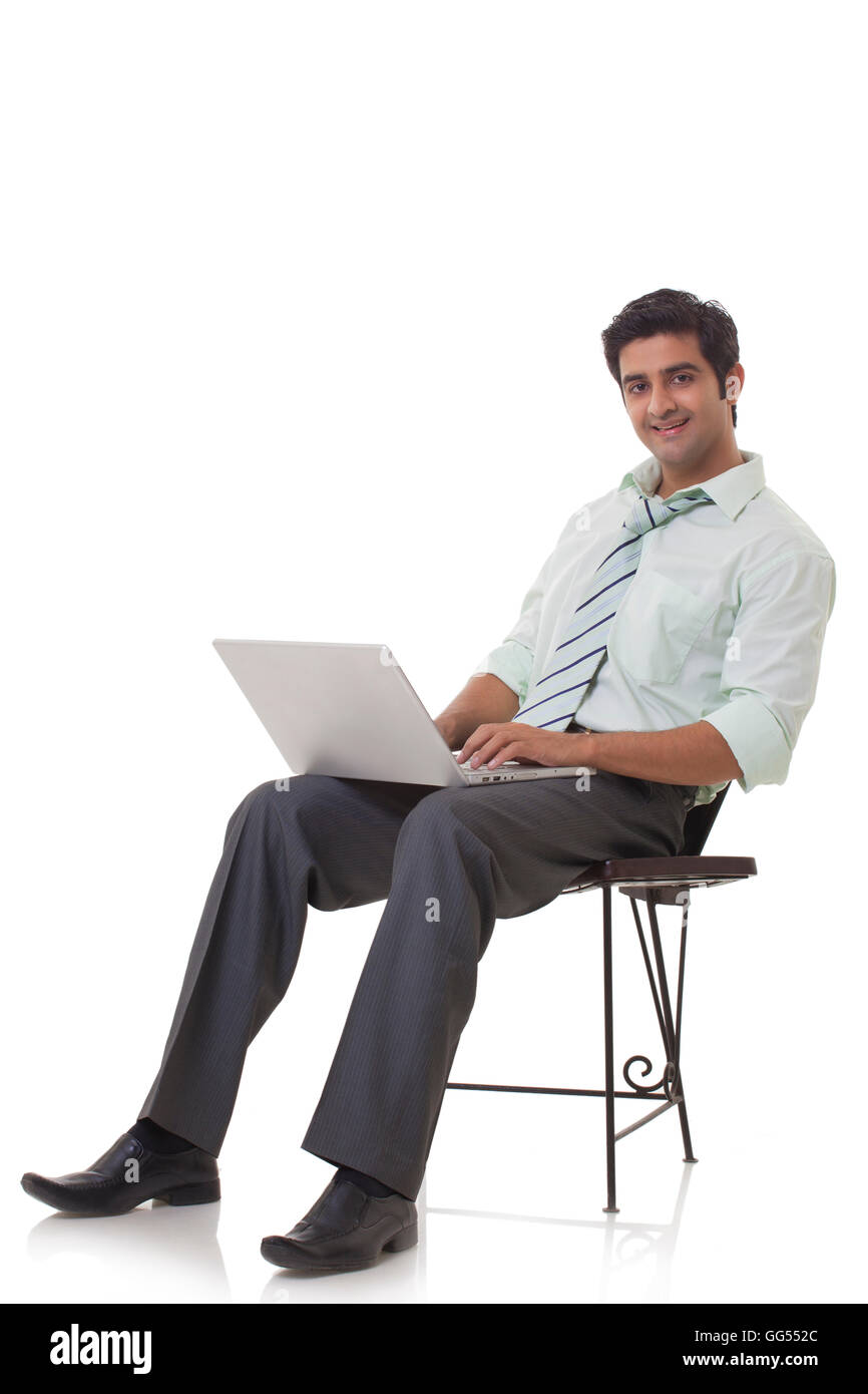 Ritratto di felice executive sulla sedia utilizzando laptop Foto Stock