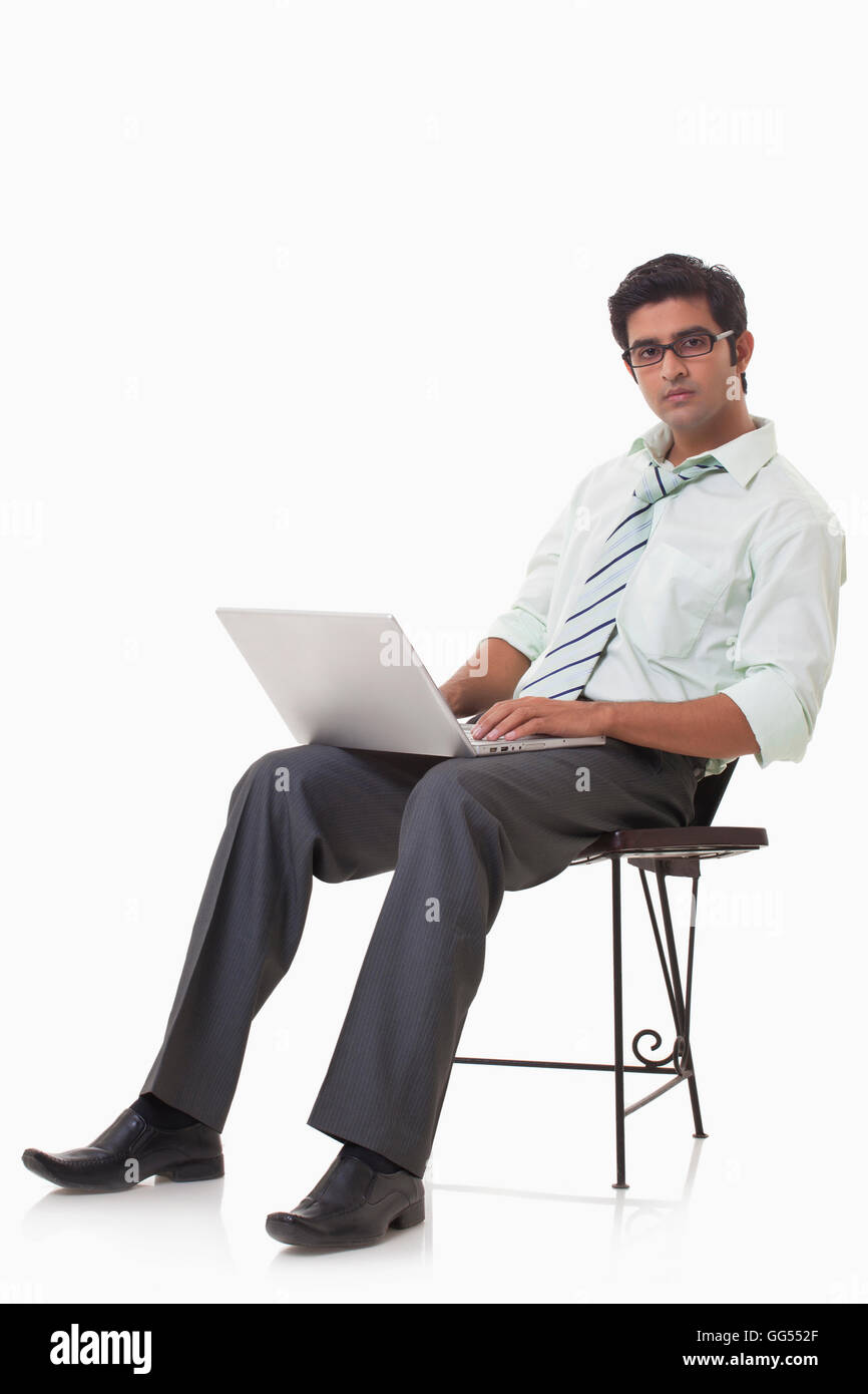 Ritratto di imprenditore belli sulla sedia utilizzando laptop Foto Stock