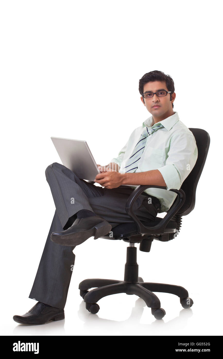 Ritratto di executive maschio sulla sedia da ufficio con computer portatile Foto Stock