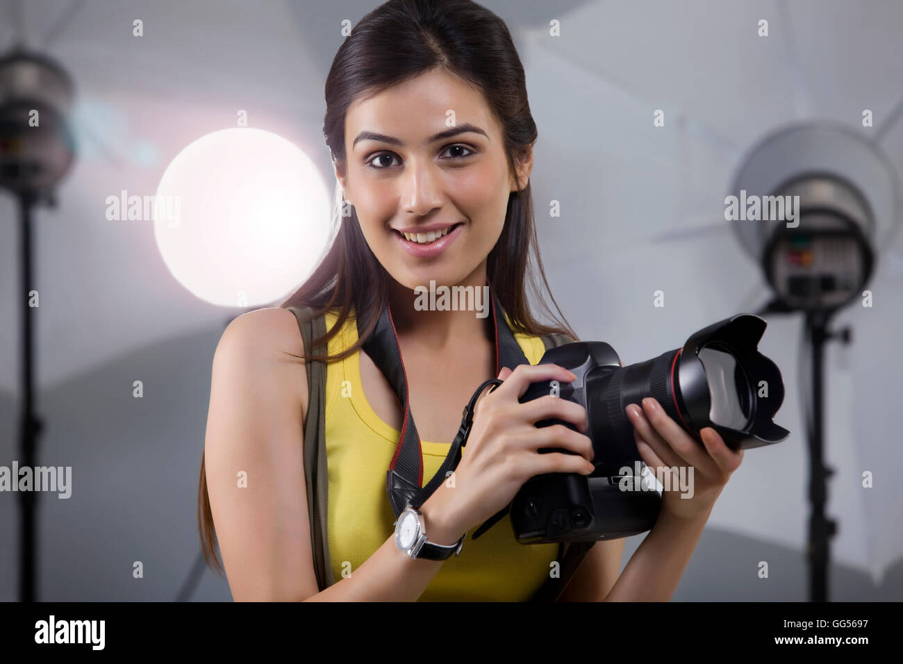 Close-up del giovane fotografo femmina con fotocamera digitale in studio Foto Stock