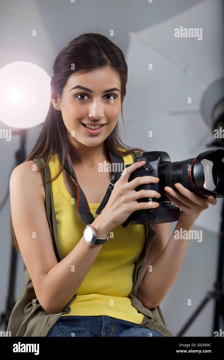 Ritratto di giovane donna fotografo con fotocamera digitale seduto in studio Foto Stock