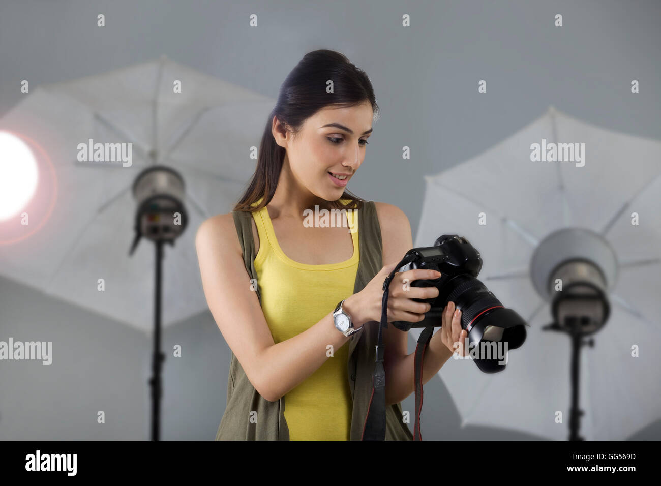 Bellissima giovane fotografo femmina cercando in fotocamera digitale Foto Stock