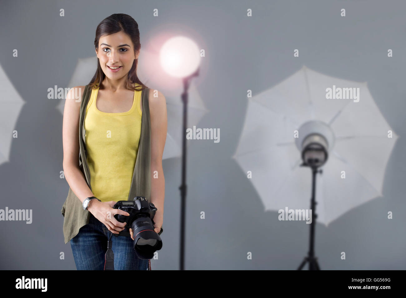 Ritratto di giovane donna fotografo con la fotocamera in piedi di fronte a Spotlight in studio Foto Stock