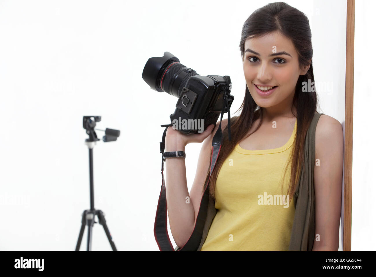 Bella giovane femmina di tenere la fotocamera contro uno sfondo bianco Foto Stock