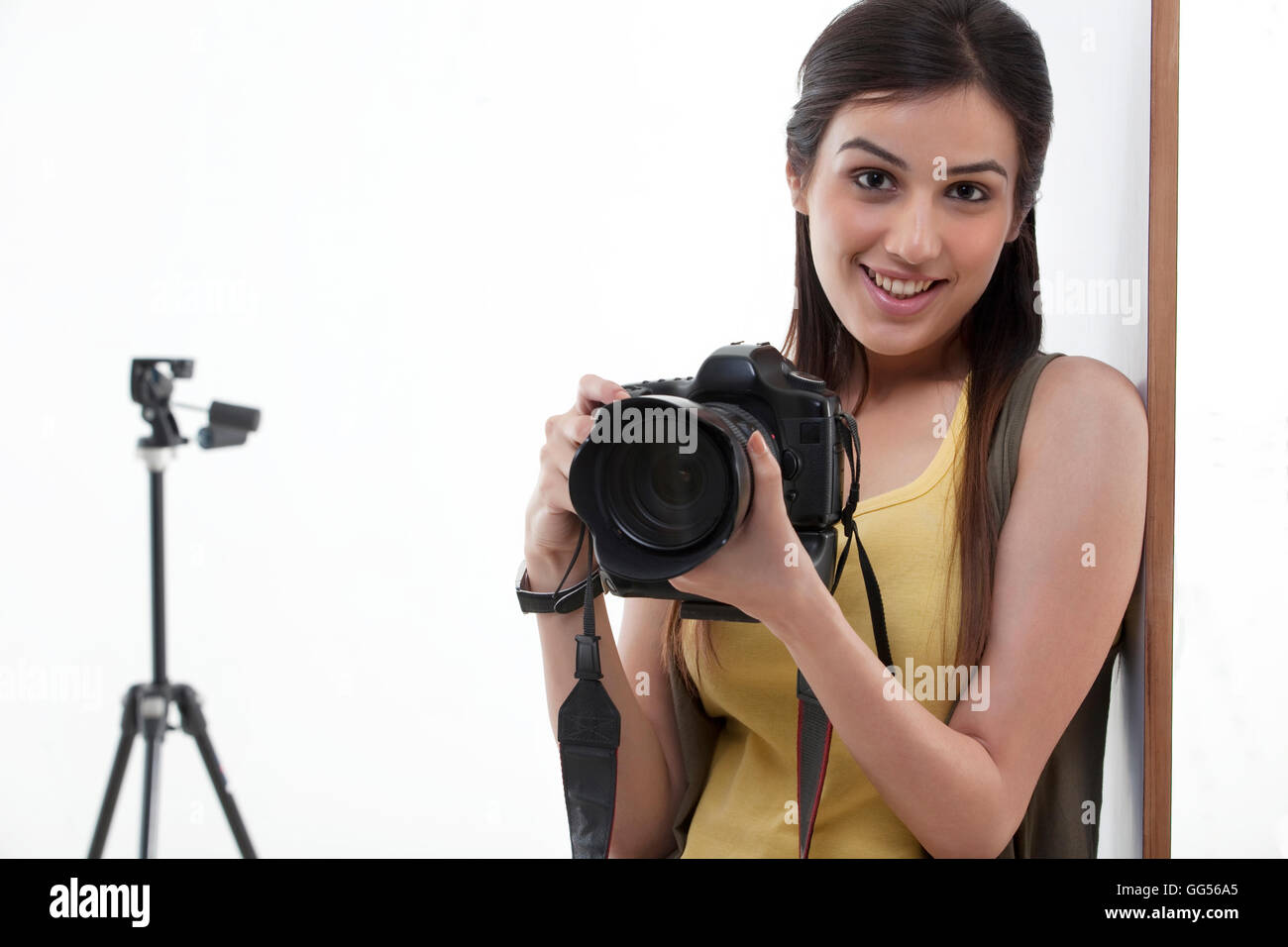 Ritratto di giovane e bella femmina di tenere la fotocamera con treppiede dietro Foto Stock
