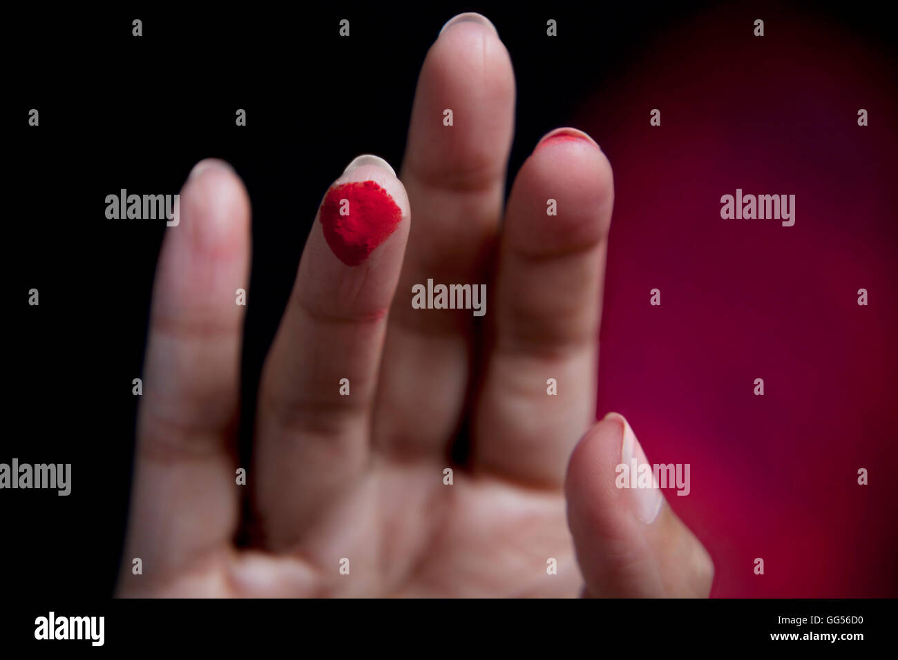 Close-up del dito umano rosso con vernice in polvere Foto Stock